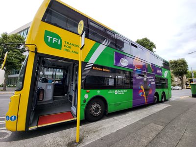 Bus on road in the green and yellow livery at bus stop