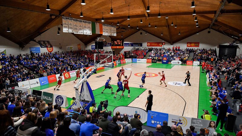 Image inside a basketball arena, with match underway and fans visible