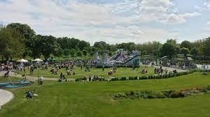 Image of green park with people walking and sitting around the grass