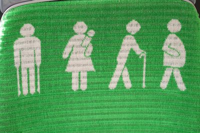Image of green seat on bus showing different people that may need priority seating