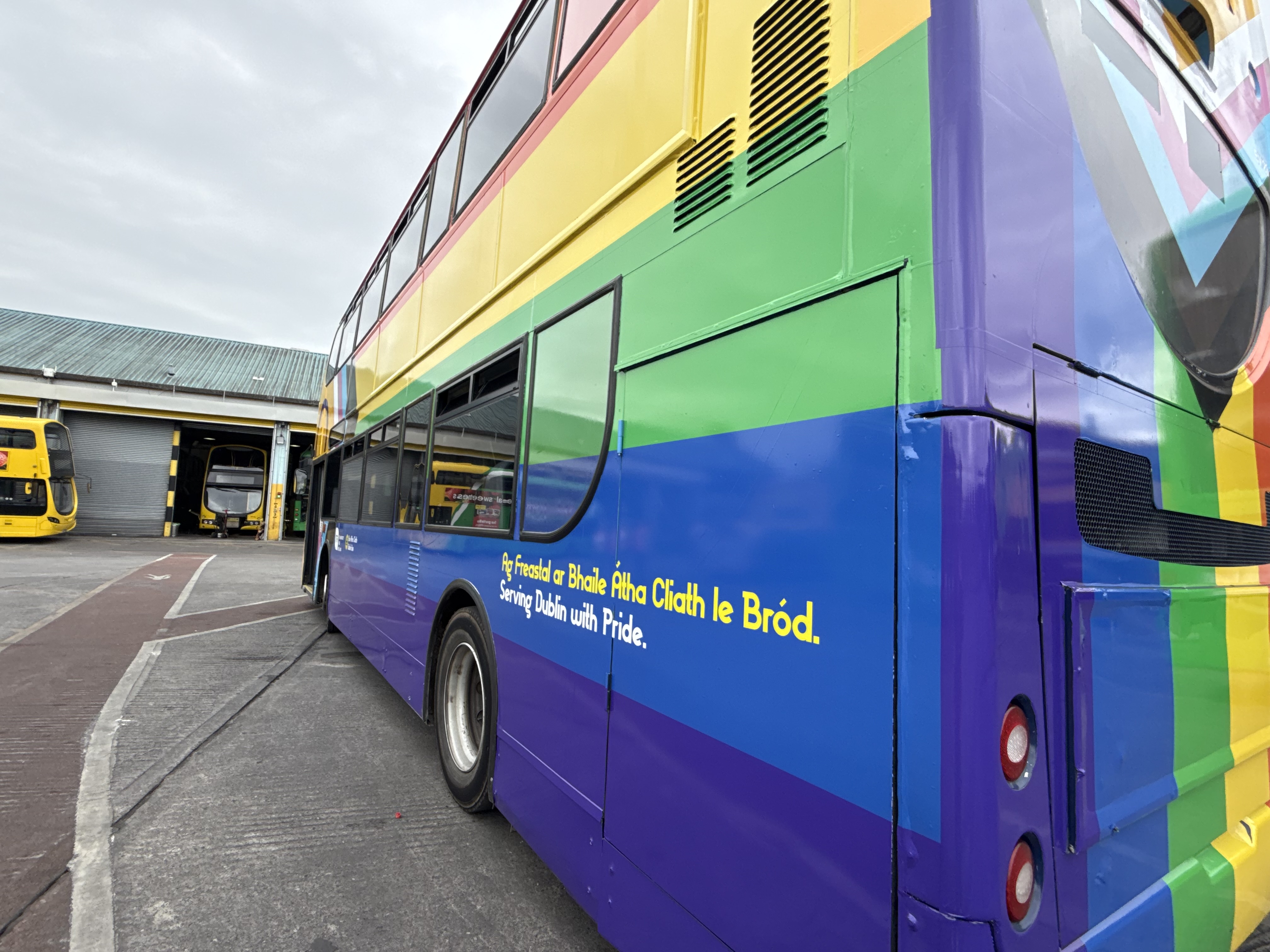 Rear view of Pride wrapped bus positioned in a bus depot