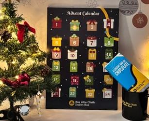 Image of a Dublin Bus advent calendar, chocolate bar and black cup with a small Christmas tree