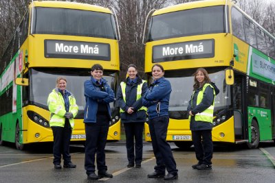 five female drivers in front of two buses 