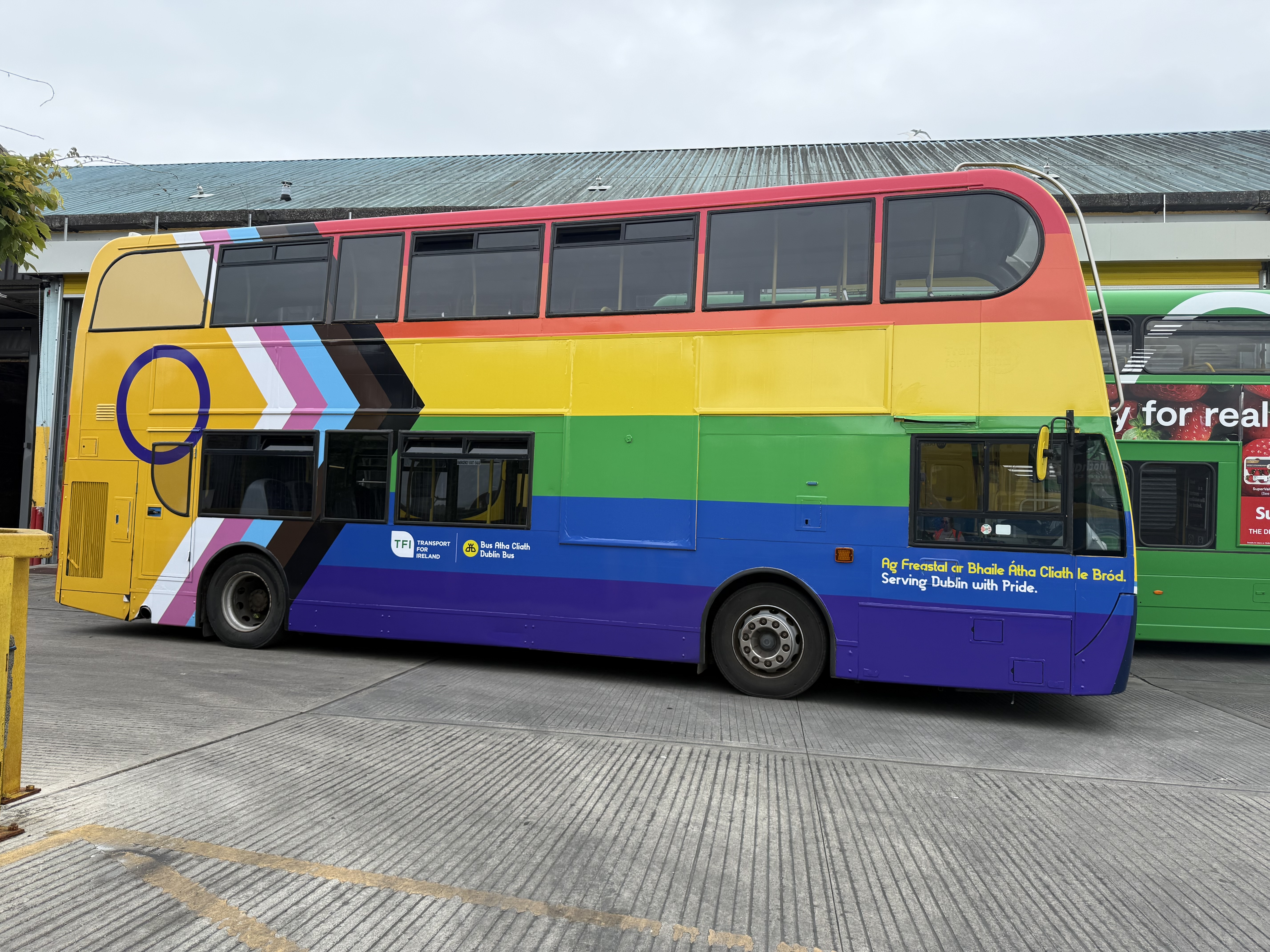 Side view of pride wrapped double decker bus parked in bus depot