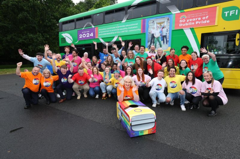 Everyone in pride tshirts in front of bus with pride wrap