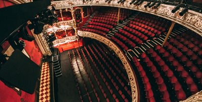 Balcony view of inside the theatre, red seating and stage.